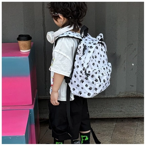 Detail of white canvas kids backpack with black paw prints and front zipper pocket