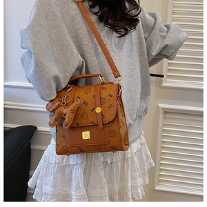 Détail du sac marron en cuir PU avec motif astronaute, logo doré et breloque chien