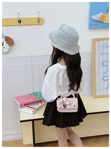 Pink tweed kids shoulder bag with pearl handle and charms on a studio background