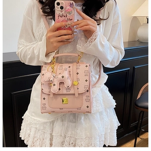 Detailed view of a pink mini quilted backpack with cat print and animal pendant