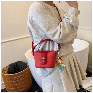 Detail of red woven bucket bag with leather trim and pearl charm shown on model