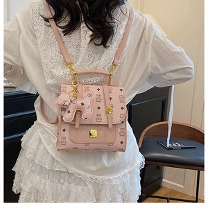 Pink monogram mini backpack with cute dog charm shown on a model in a cozy indoor setting