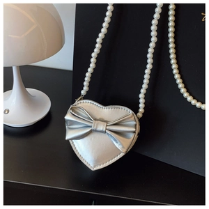 Detailed view of heart-shaped silver purse with bow accent and pearl chain strap