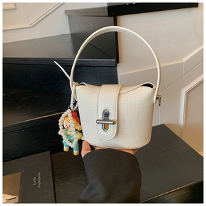 Detail of white woven mini bucket bag with silver metal lock and cute doll pendant