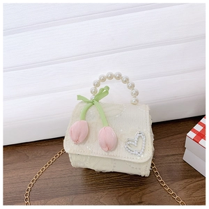 Detail view of lace mini bag with pearl handle, pink tulip charms, and gold chain strap