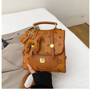 Détail d'un sac à dos marron avec imprimé chat et breloque en peluche pour chien