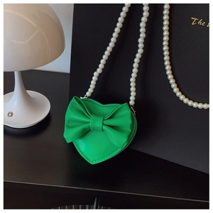 Detail of heart-shaped green girls bag with bow decoration and pearl chain strap