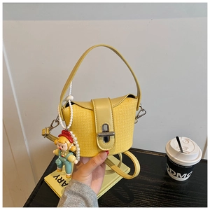 Detail of yellow bucket bag with straw texture, metal twist lock and cute girl charm