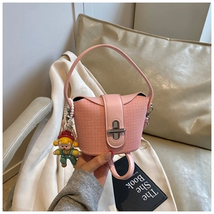 Close-up of pink bucket bag with woven texture, metal twist lock and cartoon charm