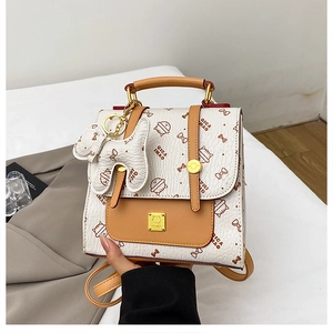 Détail d'un mini sac à dos beige avec imprimés nœuds et charm chien à la main