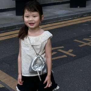 Close-up of a silver metallic chain bag with drawstring on a stylish girl's outfit