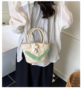 Detail of straw woven bag with crochet flowers and elegant pearl chain shoulder strap
