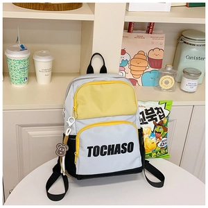 Detail of contrast color school backpack with TOCHASO logo and cute bear charm accessory