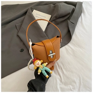 Detail of caramel woven handbag with silver twist lock and cute doll pearl charm