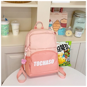 Detail of pink nylon school bag featuring TOCHASO lettering and a cute bear charm