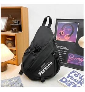 Detail of multi-compartment black chest bag with white fashion lettering and adjustable strap