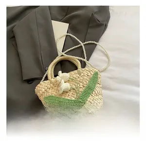 Detailed macro view of woven straw bag with crochet flowers and faux pearl chain strap