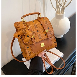 Close-up of brown pebbled leather backpack with cat prints and cute puppy charm