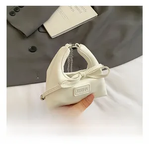 Detail of white mini handbag featuring a large 3D bow and silver metal chain strap