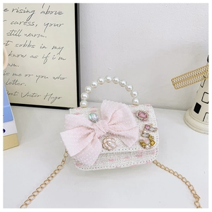 Detailed view of kids pearl handle handbag featuring pink bow and tweed texture