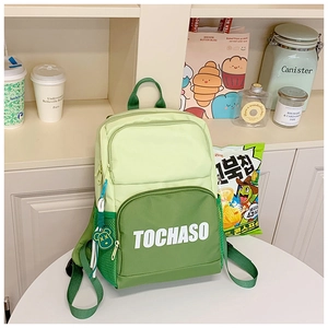 Detail of green contrast backpack with TOCHASO letters and cute bear pendant charm