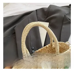 Detail of hand-woven straw bag with round handle and crochet flower charm