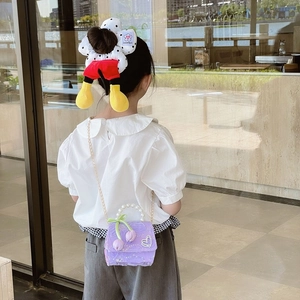 Girl's purple sequin shoulder bag with pearl handle and bow, paired with polka dot hair tie