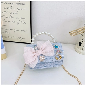 Detail of blue tweed mini bag featuring pearl handle and oversized pink mesh bow