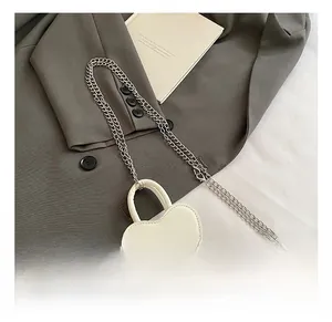 Détail du mini sac blanc en forme de cœur avec chaîne argentée et fermeture éclair