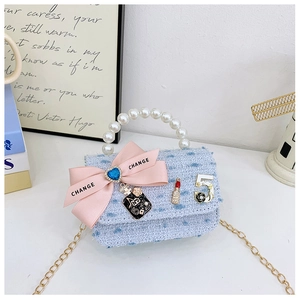 Detail of light blue tweed mini bag with pearl handle and pink bow charm