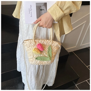 Detail of straw bag with crochet tulips and pearl chain strap for summer seaside vacation