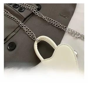 Détail d'un mini sac blanc en forme de cœur avec chaîne argentée et gaufrage