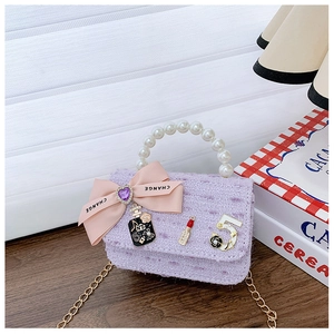 Detailed view of purple tweed mini bag with pearl handle, pink bow and N5 charms
