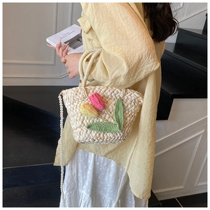 Detail of hand-woven straw bag with crochet tulips and pearl chain strap for summer