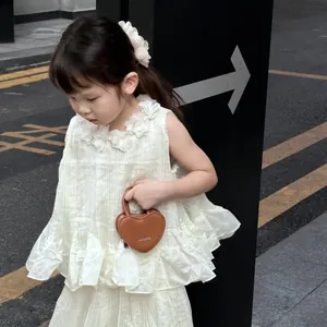 Détail d'un mannequin enfant tenant un sac en cuir marron en forme de cœur avec logo doré