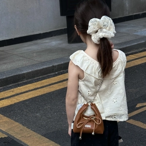 Rear view of a girls brown crossbody bag with metal chain and lace hair scrunchie