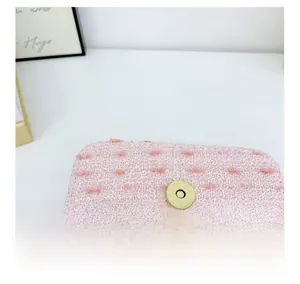 Close-up of pink tweed fabric texture and a round golden magnetic clasp on a girl purse