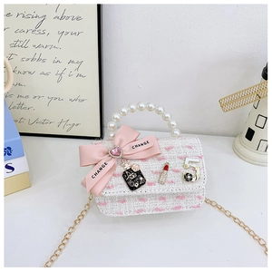 Detail of pink bow and camellia charms on a white tweed mini pearl handbag