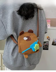 Détail du sac bandoulière Capybara avec peluche de tortue verte dans une poche bleue