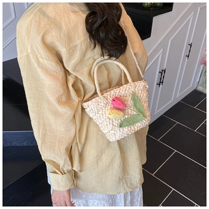 Detail of woven straw bag with handmade crochet tulip flowers and pearl chain strap