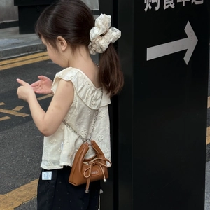 Detail of a mini brown leather handbag with bow and chain strap on a young girl