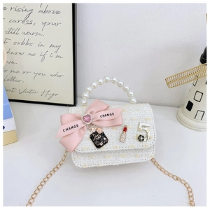 Close-up of mini white tweed handbag with faux pearl handle and pink bow charm details