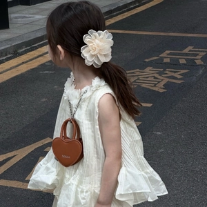 Détail d'un sac bandoulière marron en forme de cœur avec chaîne pour petite fille