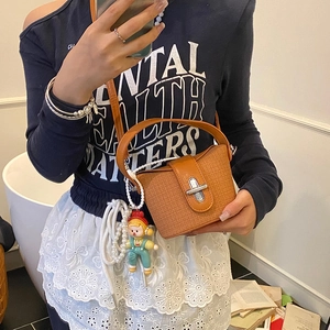 Brown textured mini bucket bag with doll pendant and pearl chain for casual wear