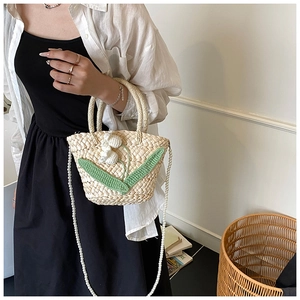 Detail of woven straw bag with floral accents and elegant pearl chain strap
