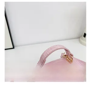 Détail de la poignée en cuir croco rose avec ferrures métalliques dorées polies