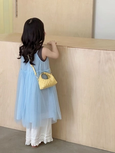 Detail einer gelben Mini-Umhängetasche für Mädchen, kombiniert mit blauem Kleid