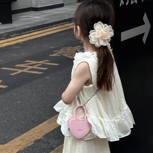 Mini sac coeur rose en cuir avec chaîne en métal sur une robe blanche à volants