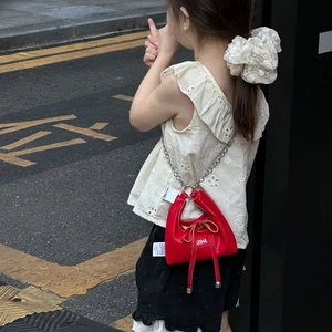 Detail of red leather girls' mini bag with bow decoration and silver metal chain strap