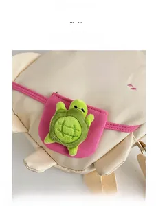 Gros plan détaillé d'un sac en toile crème avec broderie et breloque tortue en peluche verte